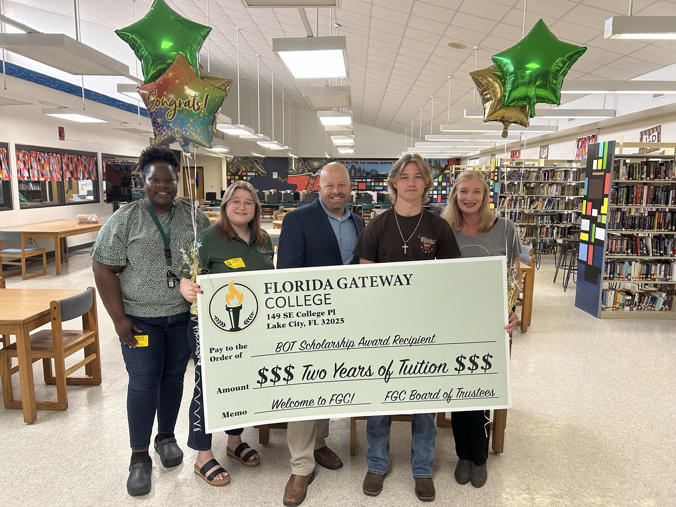 BOT Scholarship recipient and staff with large check and balloons