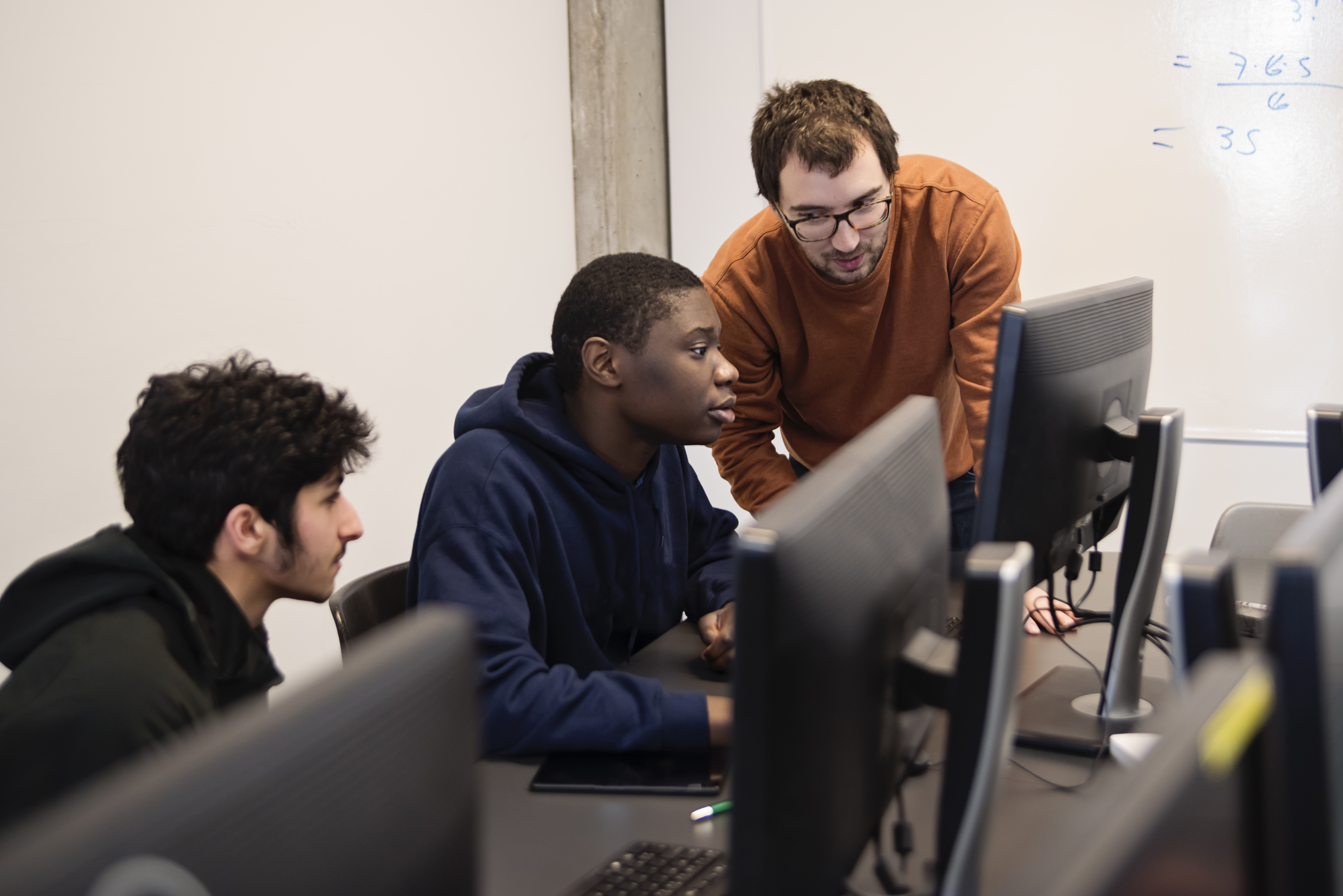 college students with teacher in programming classroom
