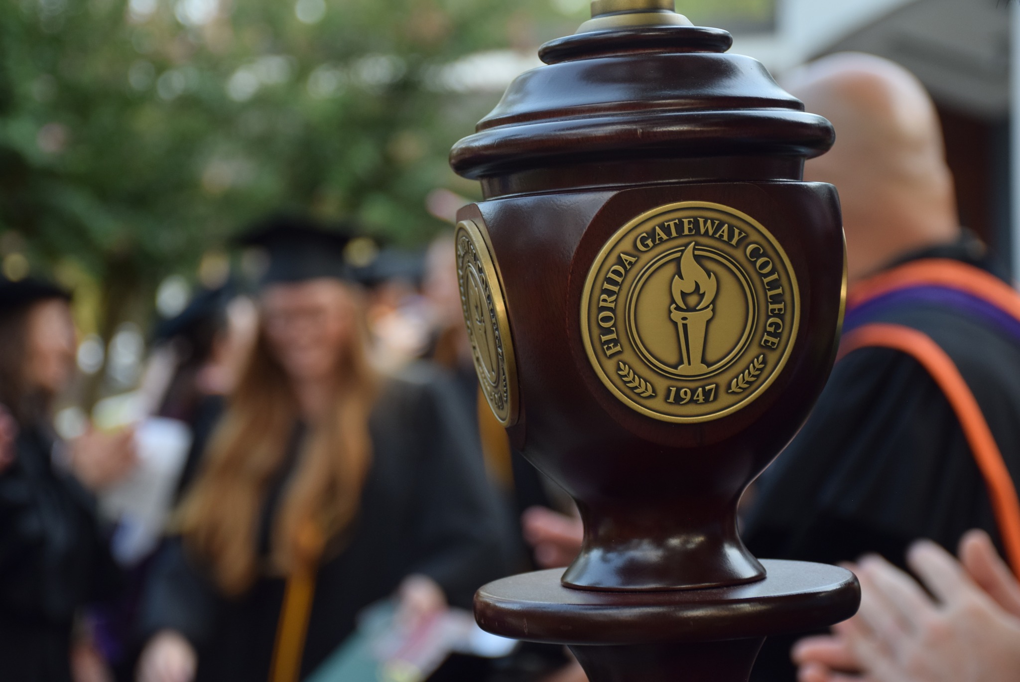 Ceremonial Mace with FGC seal; graduates in background.