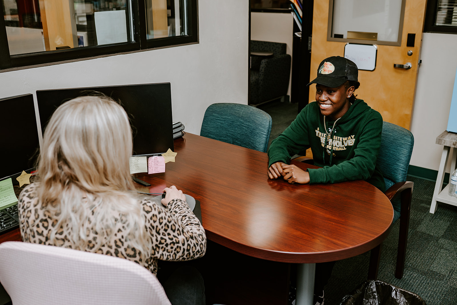 Student sitting at desk across from advisor.
