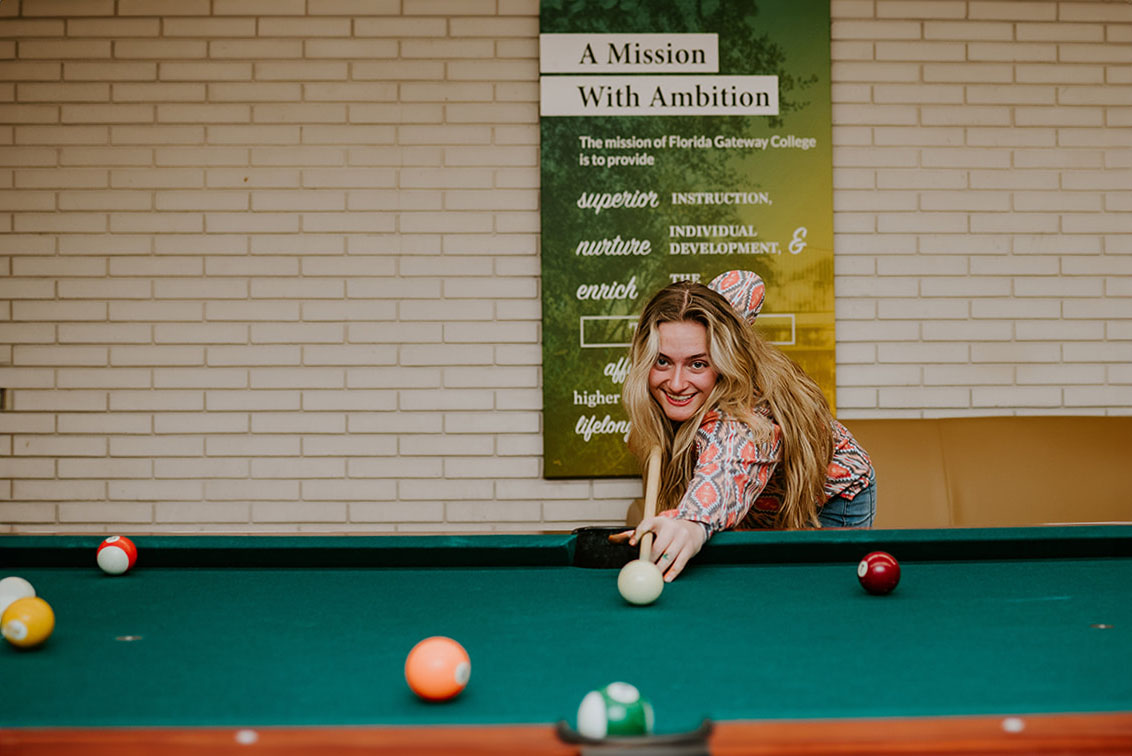 Female student playing pool in the student center