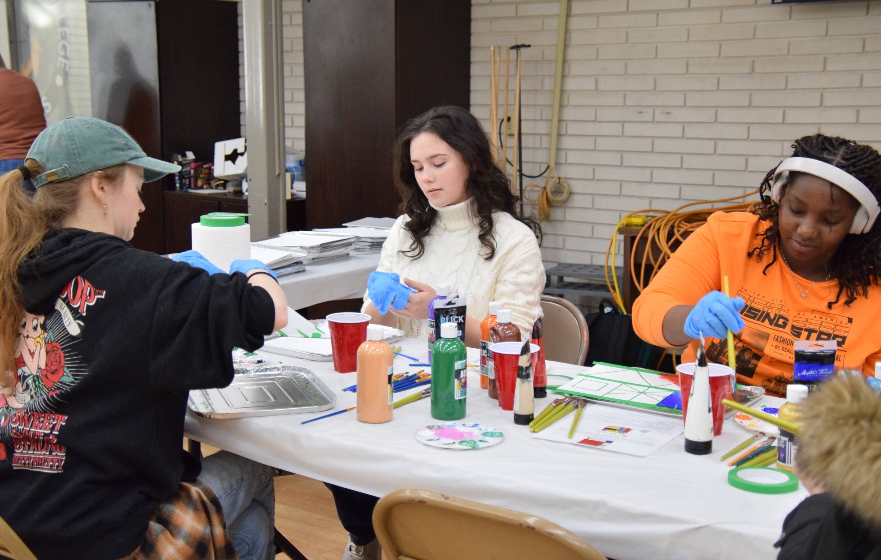 Three students working on painting art project in the student center