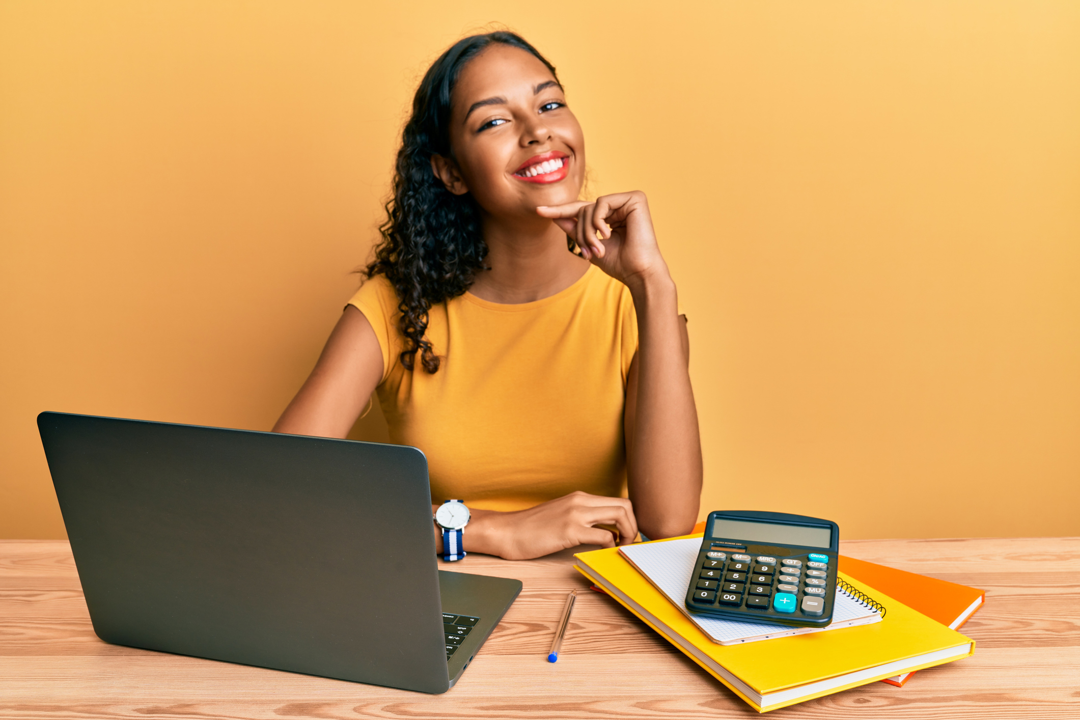 Student smiling with laptop and calculator Student smiling with laptop and calculator