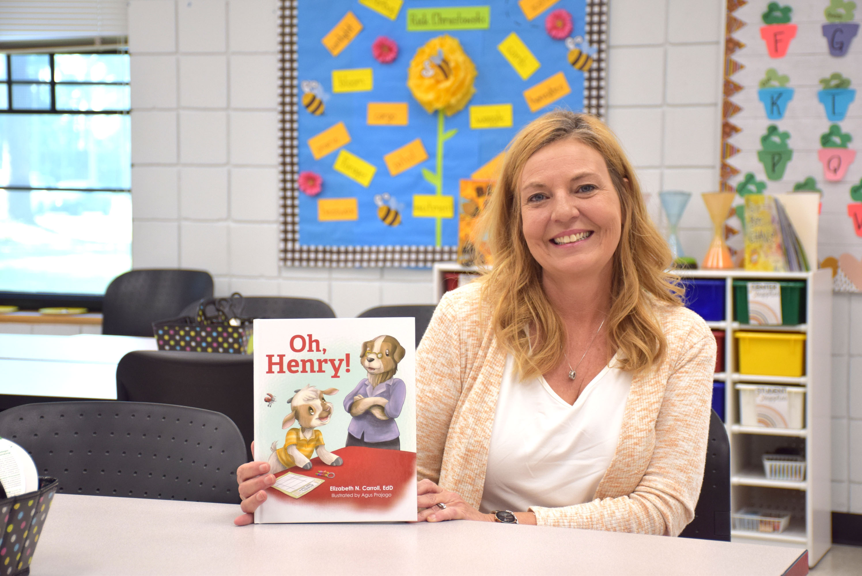 Woman seated at table and holding a children's picture book