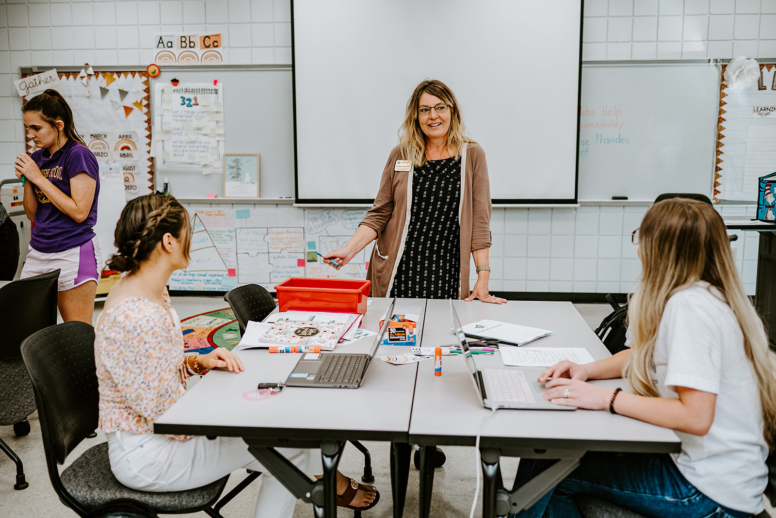 Education professor stands teaching college students in classroom.