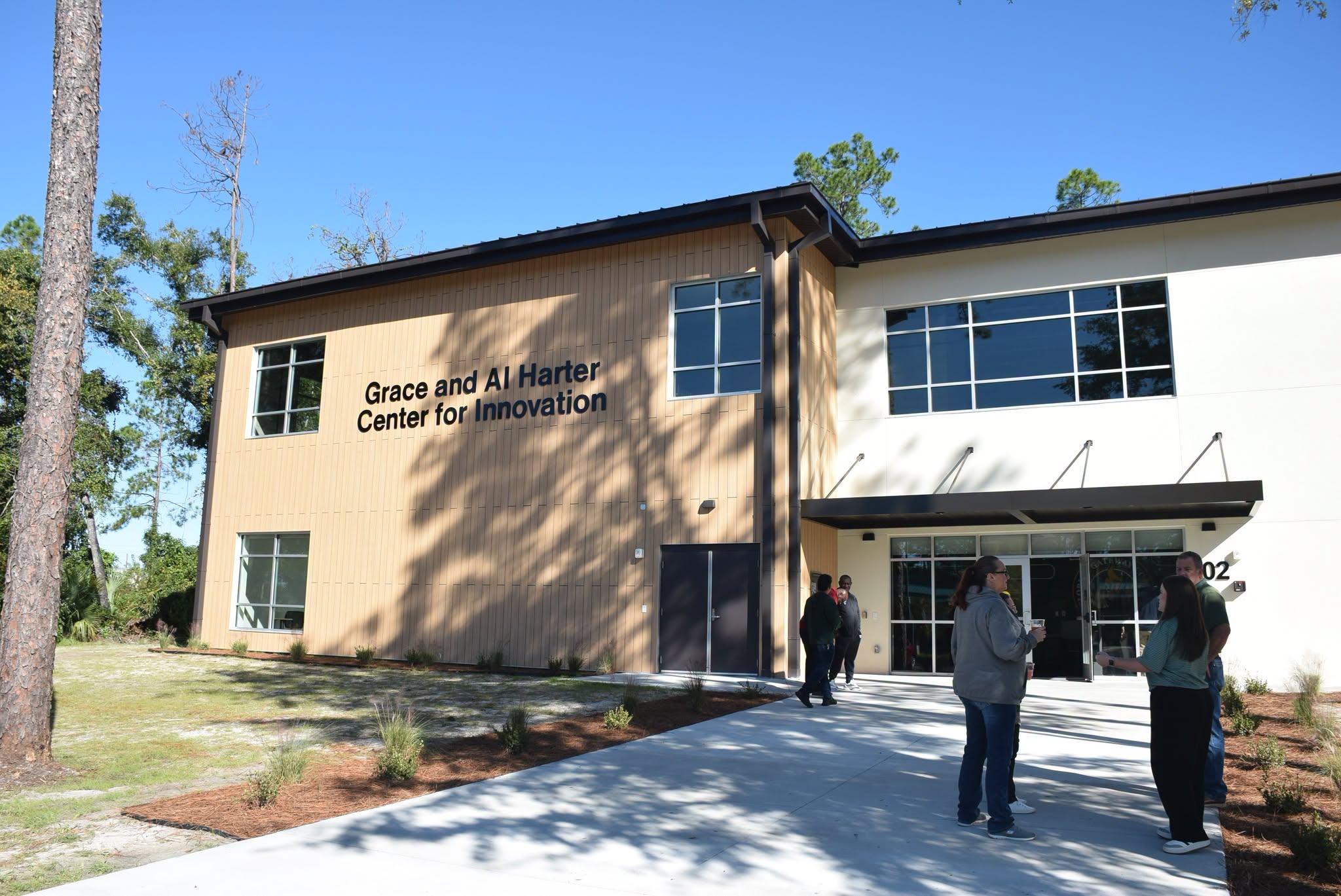 Exterior of Florida Gateway College’s Grace and Al Harter Center for Innovation, a two-story building with large windows, landscaped grounds and several people gathered near the entrance.