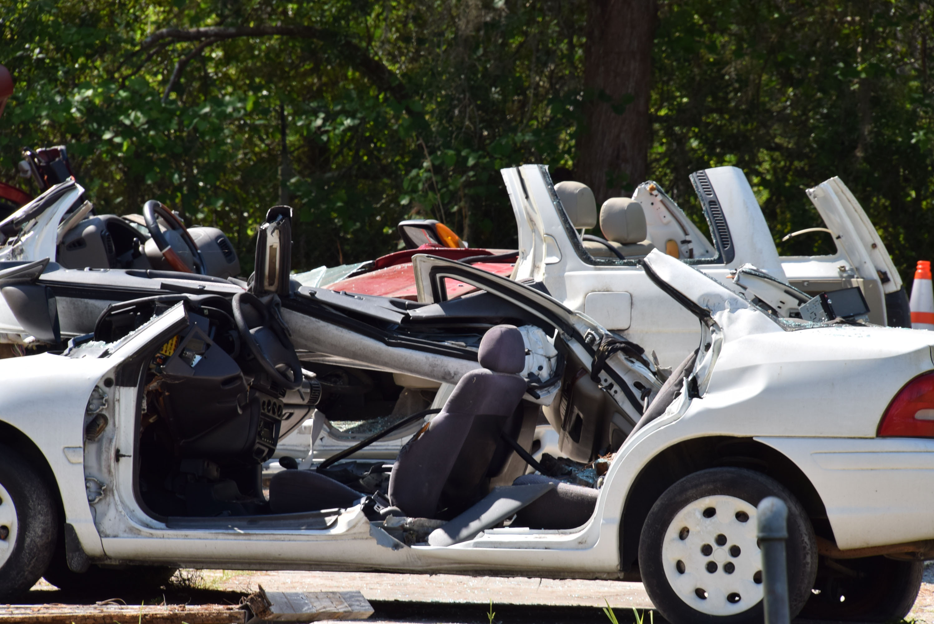 A white car with doors revoved and roof cut off. Other vehicles in background